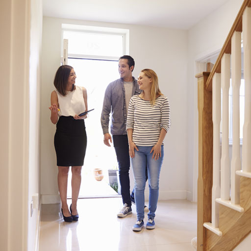 Realtor and couple standing in the entryway of a house they are viewing.