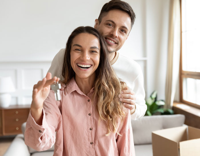Happy couple holding the keys to their new house.